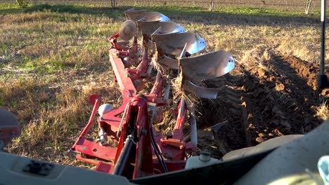 farmer lowering reversible plow in the ground, plowing soil for seeding