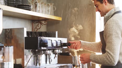 waiter steaming milk at the coffee machine