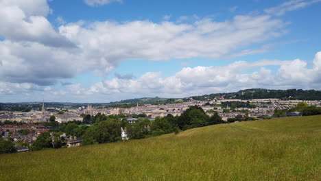 right to left pan shot of the city of bath skyline from hillside lookout on a sunny summer’s day with blue sky - white fluffy clouds