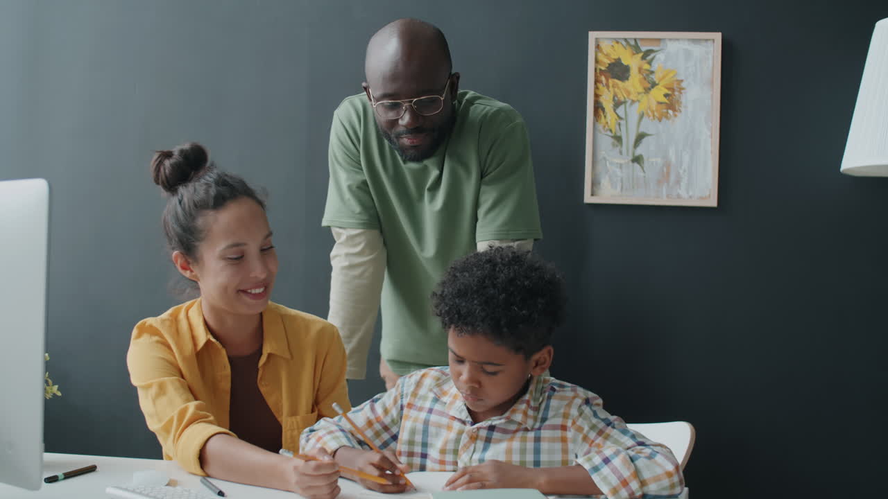 Afroamerikanischer Junge macht Hausaufgaben mit den Eltern zu Hause.