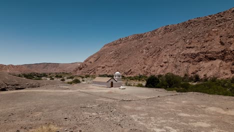 experience the mesmerizing allure of a verdant oasis in the heart of atacama's arid landscape through stunning drone footage that captures a small church nestled in a picturesque valley from above