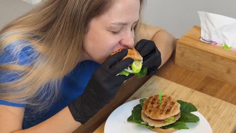 mujer comiendo una hamburguesa con guantes
