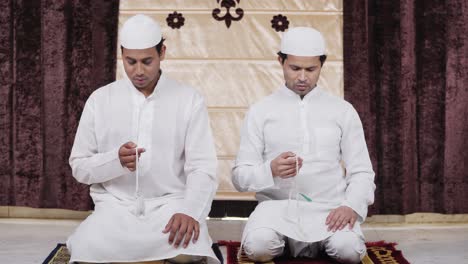 muslim men praying to allah god using praying beads