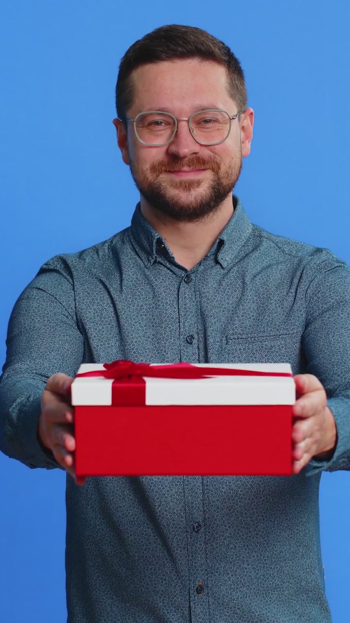 Uomo sorridente che presenta un regalo di compleanno. La scatola di regali allunga le mani. Promozione, sconto.
