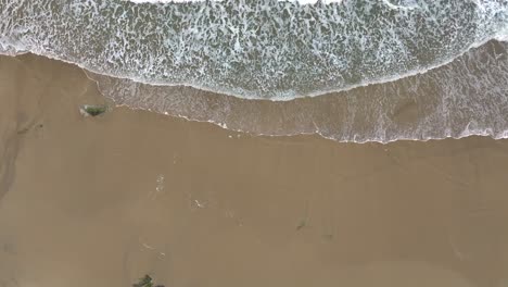 Luftaufnahme-über-Schäumende-Wellen-Des-Meeres,-Die-Auf-Einen-Sandstrand-Laufen---Drohnenaufnahme