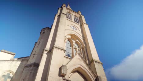 Looking-up-an-impressive-and-mighty-cathedral-in-the-sun,-powerful-symbol-of-faith-and-hope,-with-blue-sky