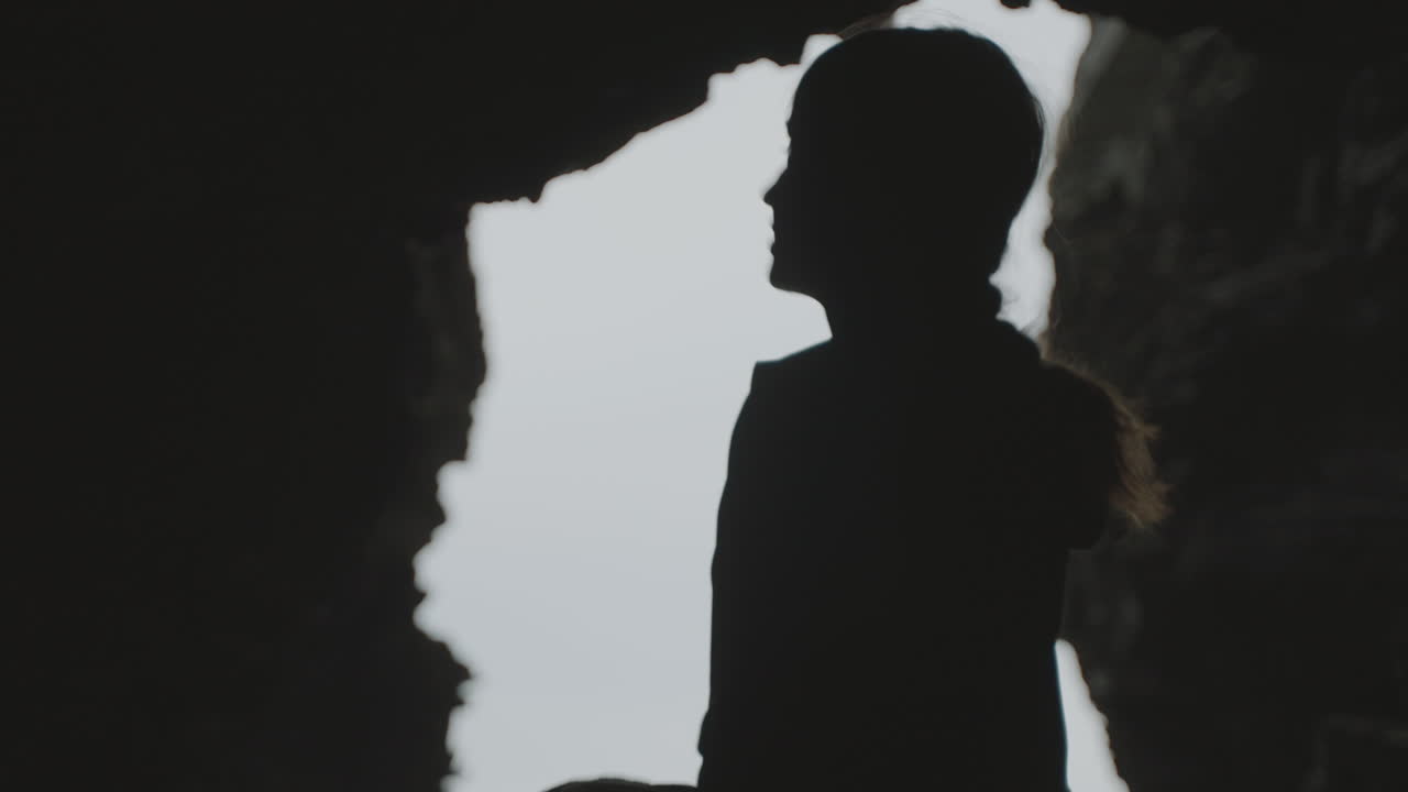 Person Silhouetted in a Cave Entrance
