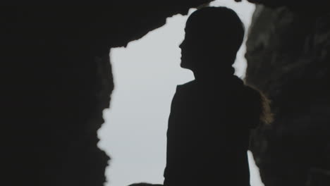 person silhouetted in a cave entrance