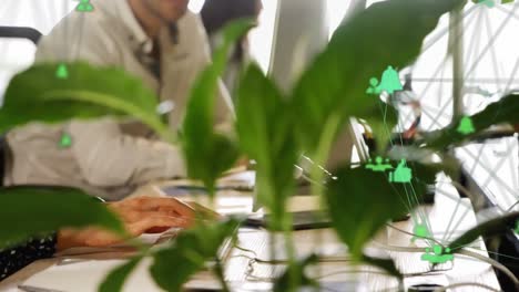 animación de globos de iconos digitales contra la sección media de una mujer usando una computadora en la oficina