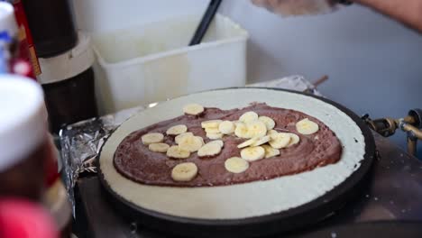 las manos cierran cortando rodajas de plátano que caen en una deliciosa crepe de nutella