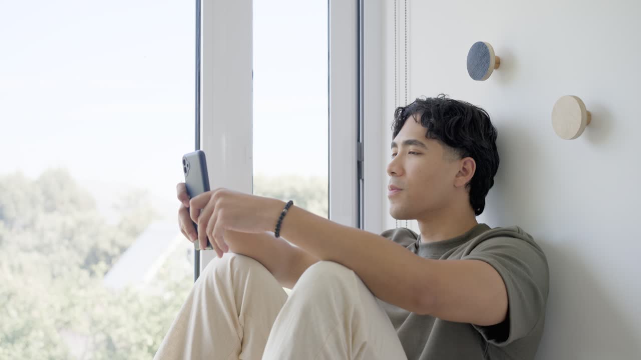 音楽が始まり、細い窓際に座った男性が携帯電話を持ち、ちらりと見て一緒に歌っている。
