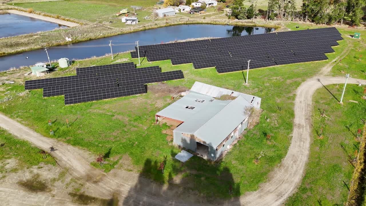 Drone footage captures a solar farm amidst lush greenery and ponds, highlighting sustainable energy in a serene rural setting