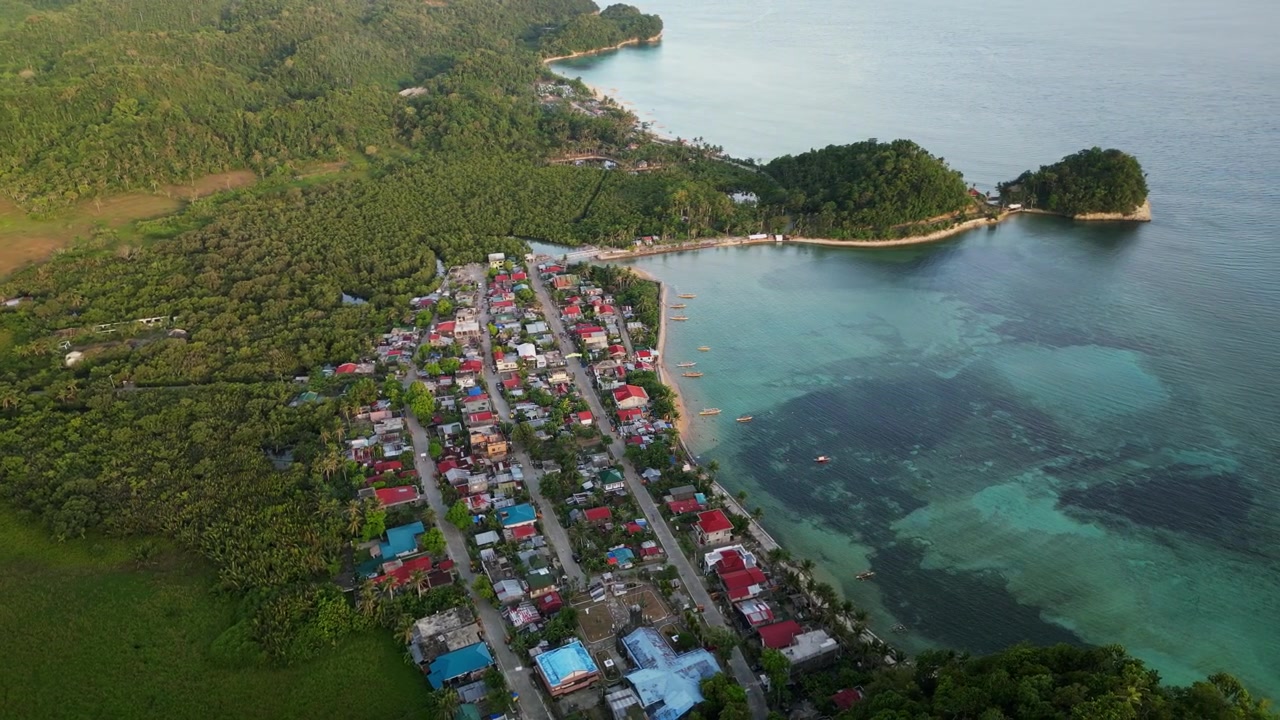 Orbita aerea panoramica di Magnesia Del Norte a Virac, Catanduanes con villaggio costiero, baia limpida e lussureggianti colline tropicali.