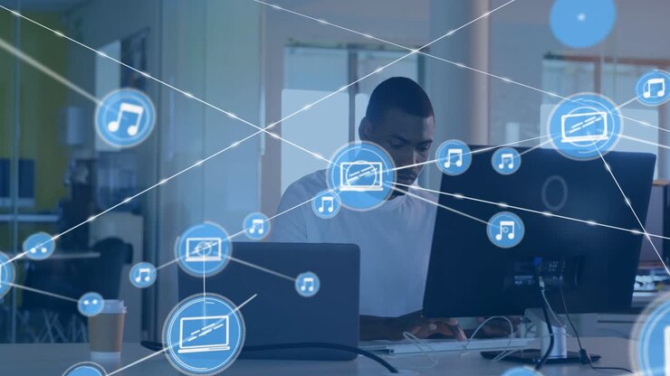 Icona blu che appare vicino al laptop, icone che si connettono dal monitor mentre un lavoratore digita, mostrando dati.