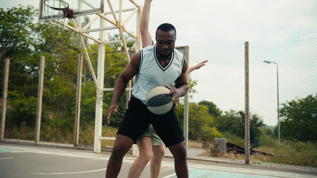 Dynamic game of basketball One of the players bypasses the other and scores a brilliant goal game at the basketball flat in the summer