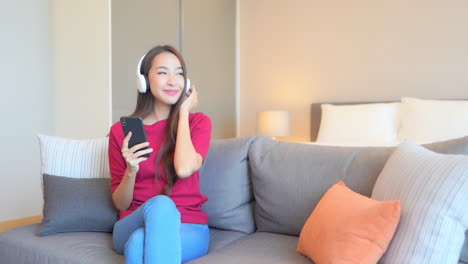 a young woman sitting on the couch enjoys the music coming through her headphones