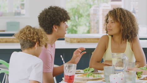 Familia-Multirracial-Sentada-Alrededor-De-La-Mesa-En-La-Cocina-De-Casa-Comiendo-Juntos