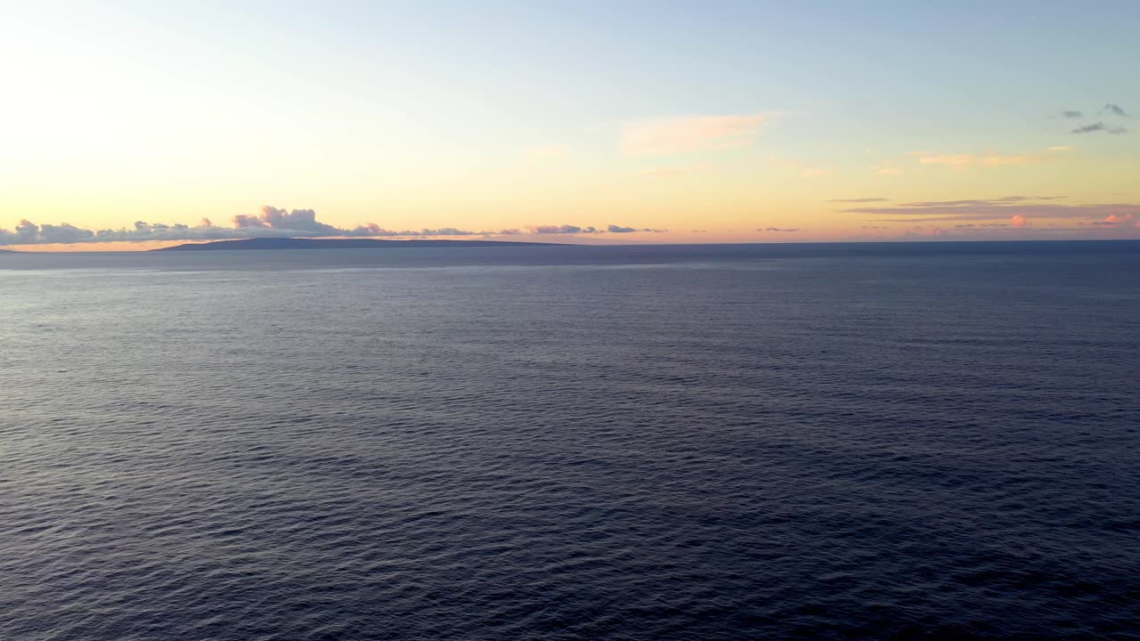 Suggestiva vista aerea al tramonto sull'oceano calmo, panorama di un'isola hawaiana all'orizzonte con un cielo dai colori vivaci.