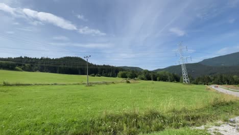 power lines through nature hills mountains during bright summer day