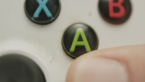 macro view of finger pressing a button of dirty game controller