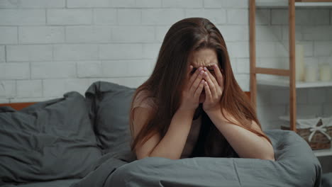 una mujer llorando en la cama.