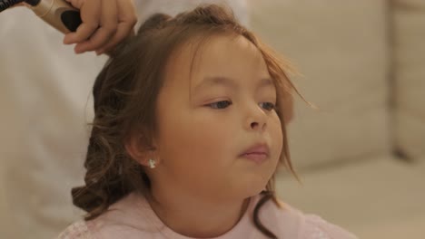 pregnant mother styling her daughter's hair at home