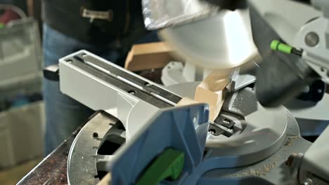 close-up of a man's hand working on a machine with a circular saw