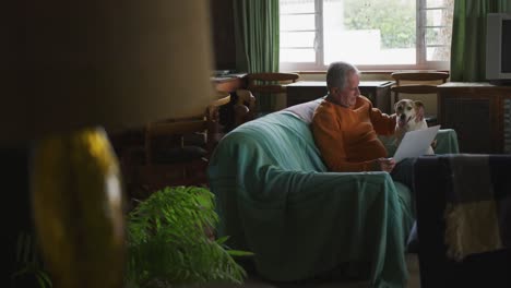 senior man and his dog on sofa at home