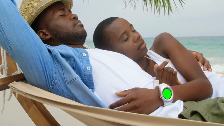 Vista laterale di una coppia afroamericana che dorme in amaca in spiaggia 4k