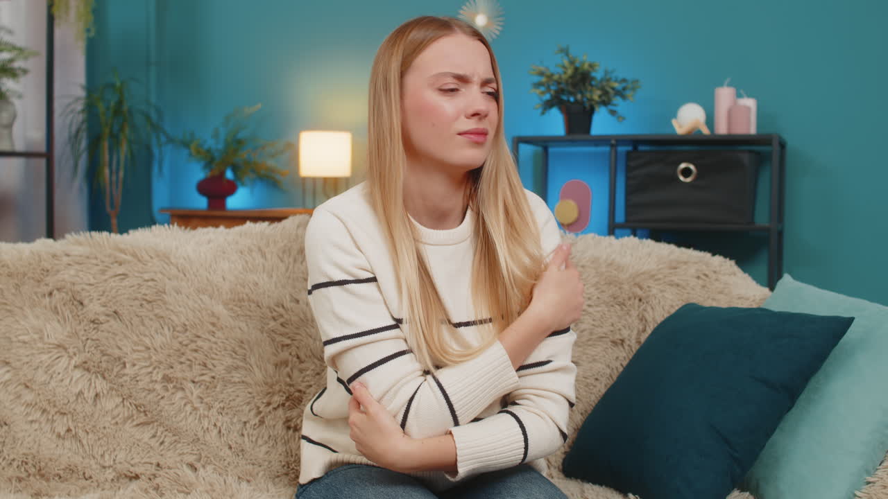 Caucasian woman abdominal stomach pain on sofa holding belly cramps suffering indoors discomfort