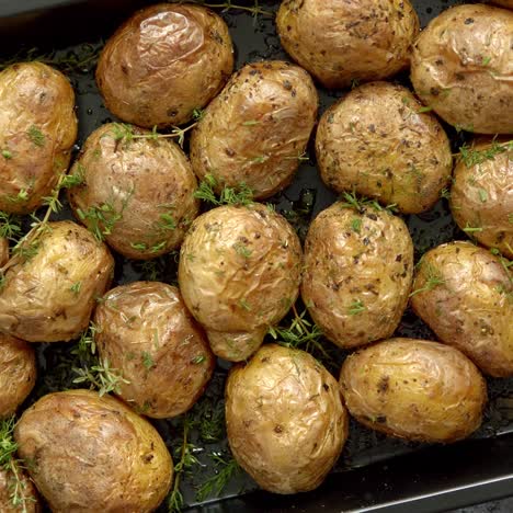 oven baked whole potatoes with seasoning and herbs in metalic tray  roasted potatoes in jackets