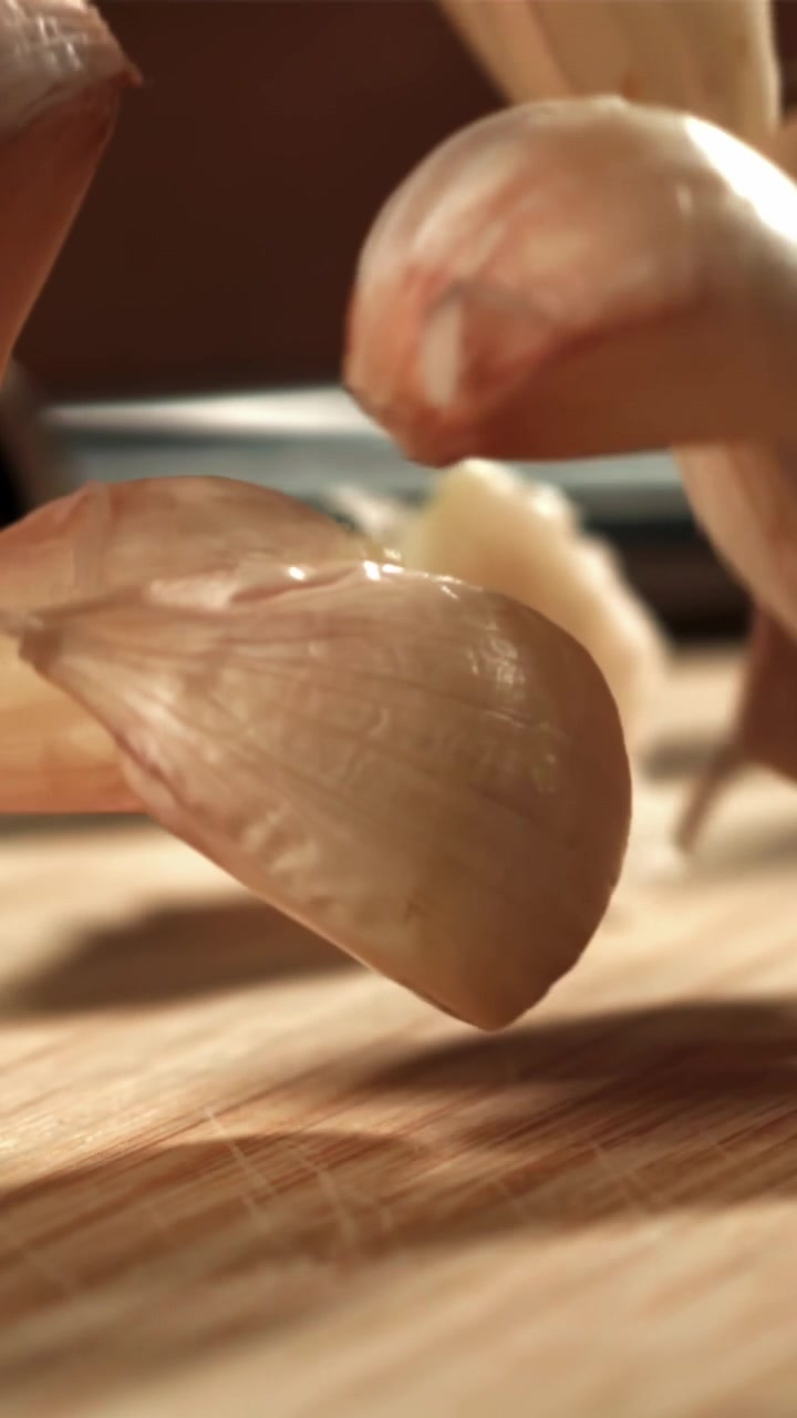 Spicchi d'aglio che cadono al rallentatore su una superficie di legno