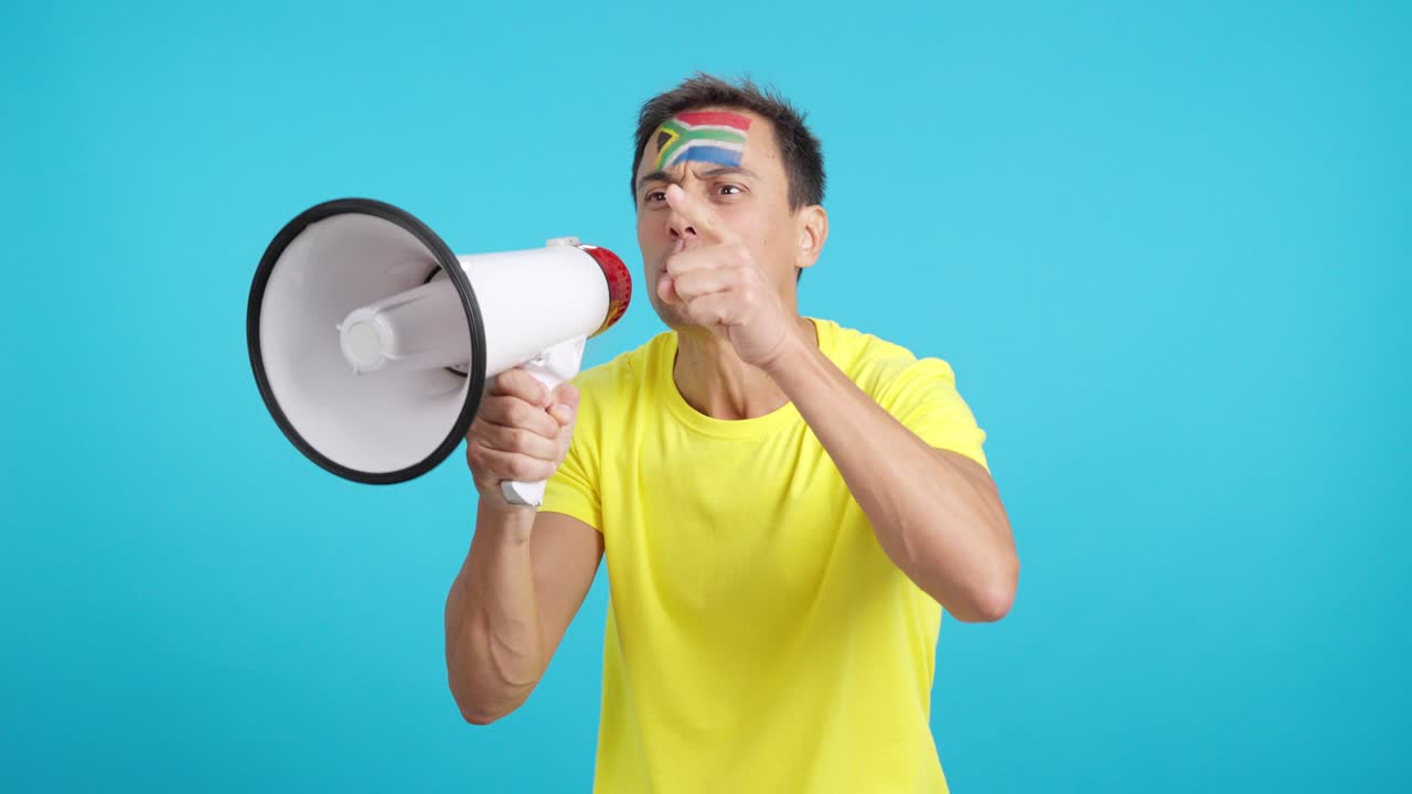 Excited man with south african flag on face using a megaphone
