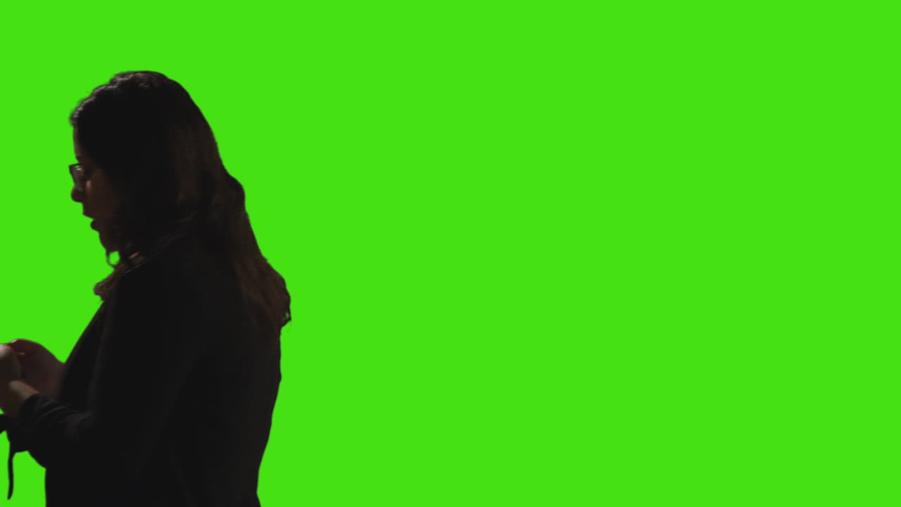 боковой вид бизнесменки, отправляющей текстовые сообщения по мобильному телефону, проходящей через кадр на зеленом экране