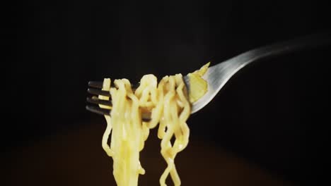 steaming ramen noodles on a fork with a black background