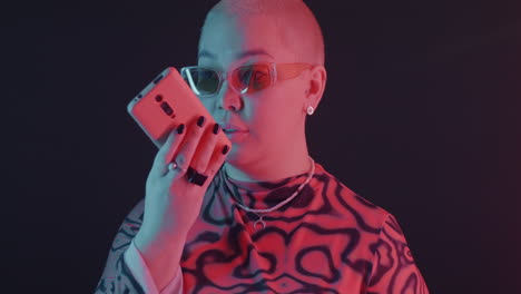 stylish plus-size woman with phone in neon light
