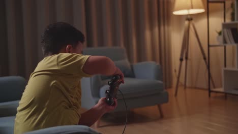 asian boy gamer siting on sofa playing car race game in living room