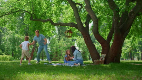 active family have fun on green park meadow. parents play with kids outside.