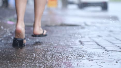 blur background shot running flipflop on the hard raining day, on the street side walk, flooding street, with rain and water, lower body part, rush hurry run finding the shelter to hide the rain