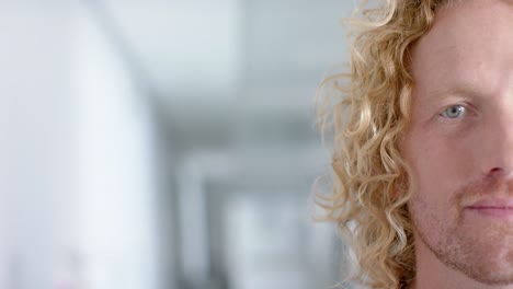 Portrait-of-happy-caucasian-male-doctor-with-curly-hair,-smiling,-copy-space,-slow-motion