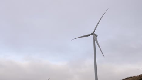 wind turbine rotating in front of overcast sky generating renewable electricity