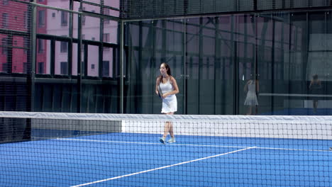 young adults playing padel tennis on blue indoor court, focusing on intense match