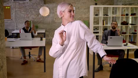 joven mujer de negocios bonita está bailando en la oficina, los colegas están aplaudiendo, concepto de trabajo, concepto de relajación