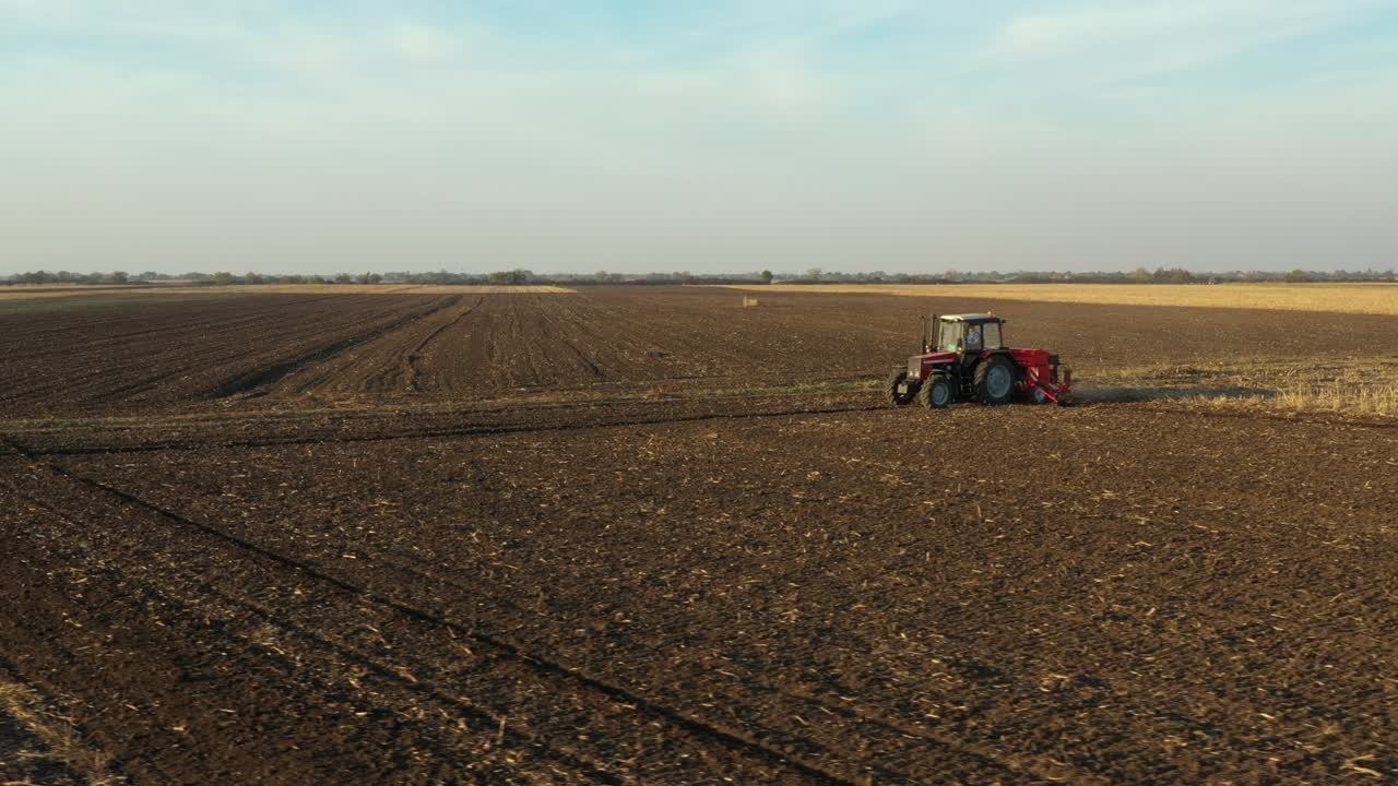 movimiento en órbita de dolly en vista aérea superior del tractor como arrastrando una máquina de siembra sobre el campo agrícola, tierras de cultivo
