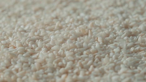 white sesame seeds pouring on full frame sesame pile background, extreme close up shot