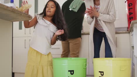 hispanic parents and daughter teaching segregating plastic and paper trash