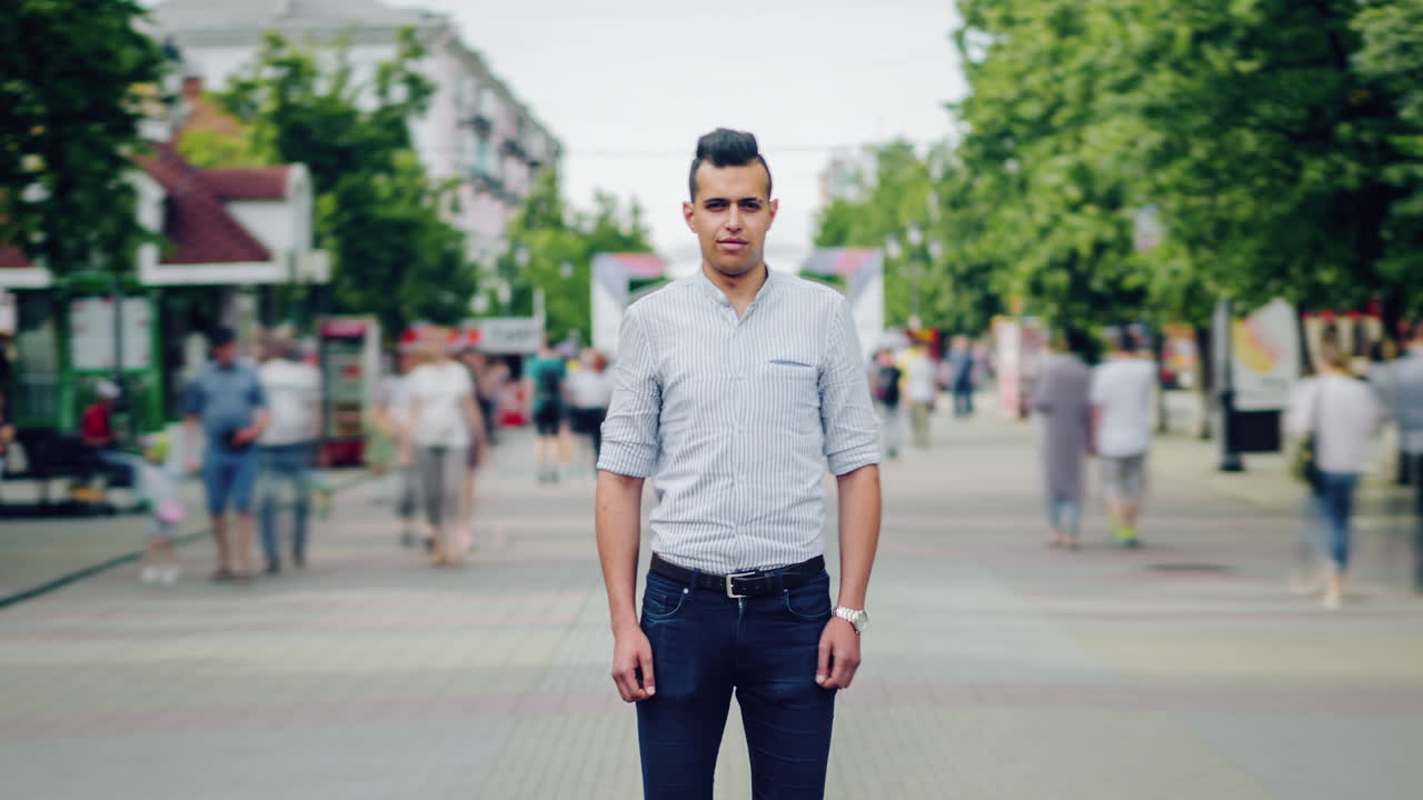 Man standing on a city street with a crowd in the background.