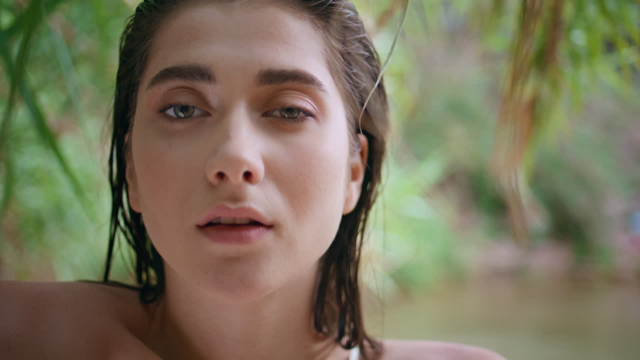 closeup hermosa mujer cara mirando cámara en la naturaleza tropical. mujer modelo posando