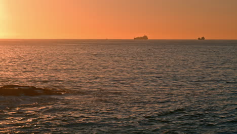 Silueta-De-Ferry-Navegando-Por-El-Océano-Al-Amanecer.-Aguas-Tranquilas-Lavando-Playa-Dorada