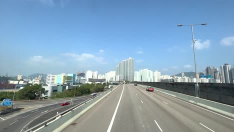 Elevated-highway-where-cars-are-taking-over-with-in-the-background-the-high-skyline-of-Hong-Kong-on-a-sunny-day
